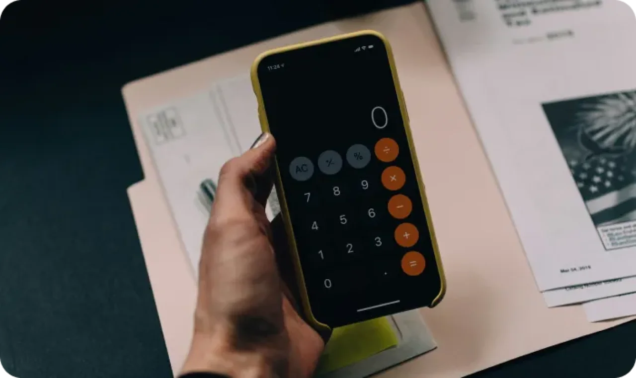 Calculator app on a smartphone next to documents.