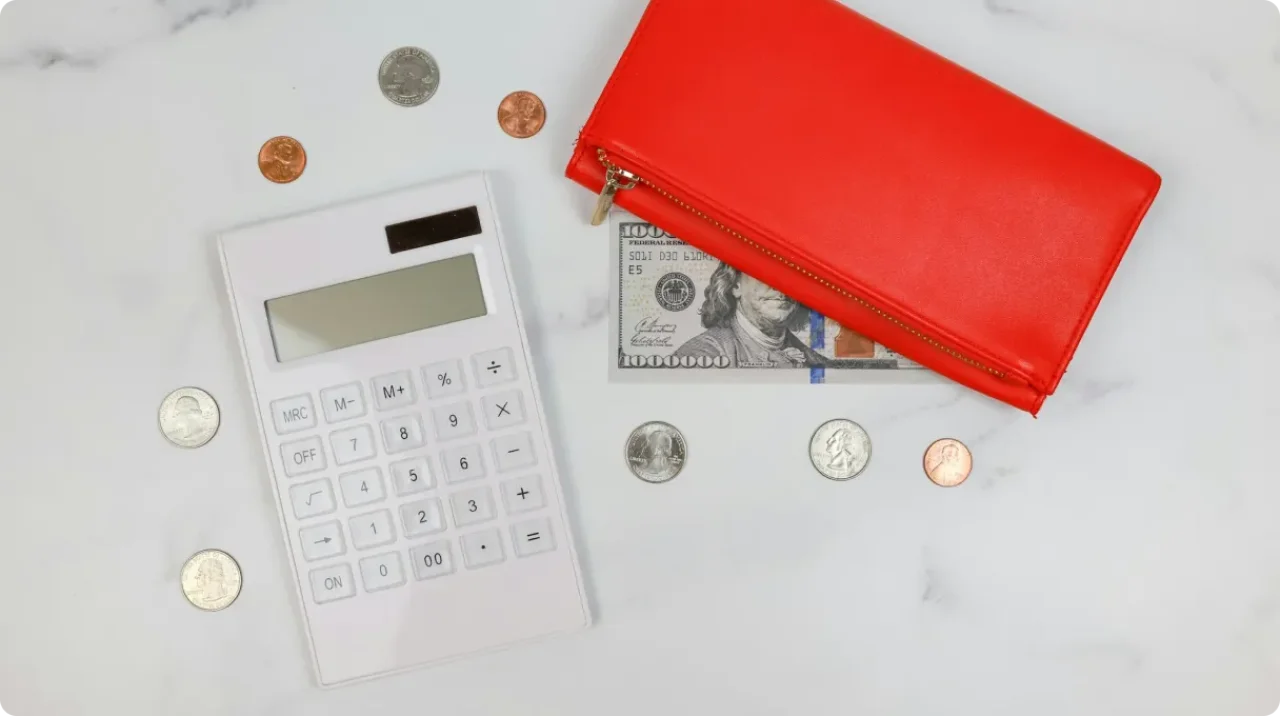 Calculator, coins, and a red wallet with cash.