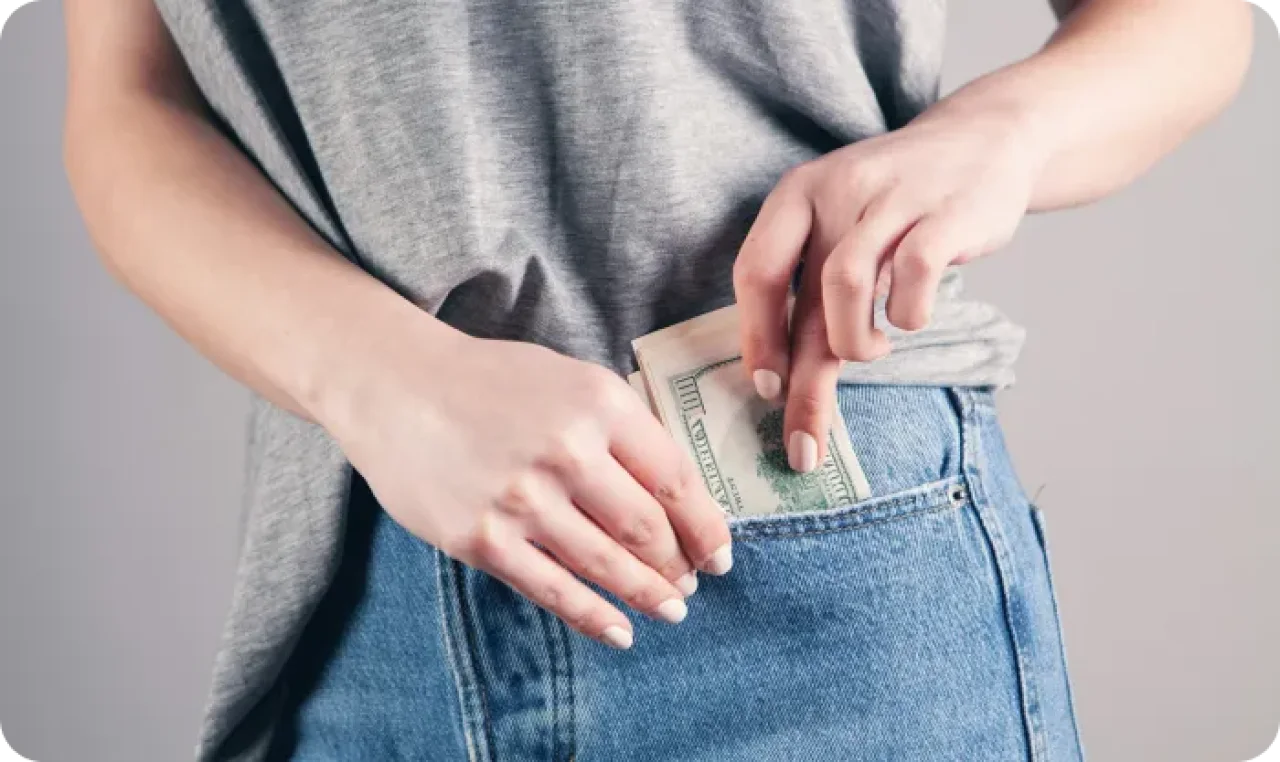 Person putting cash into back pocket of jeans.