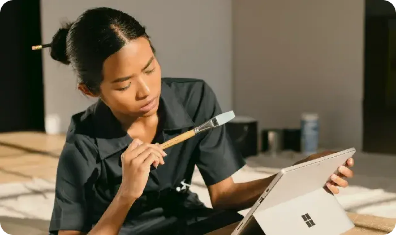 A woman sitting on a box holding a paintbrush