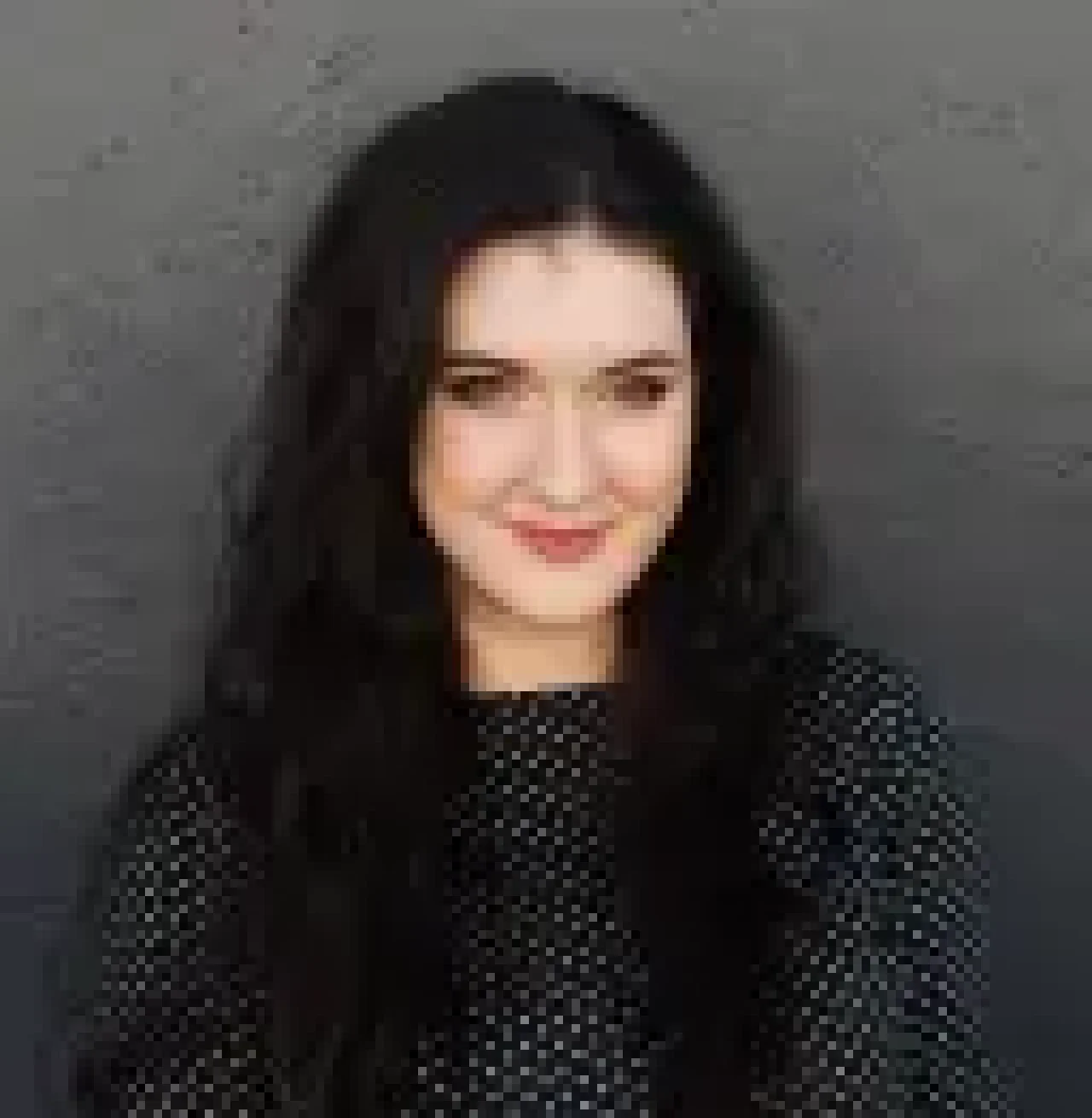 Carrie Buchholz-Powers smiling in front of a dark gray background