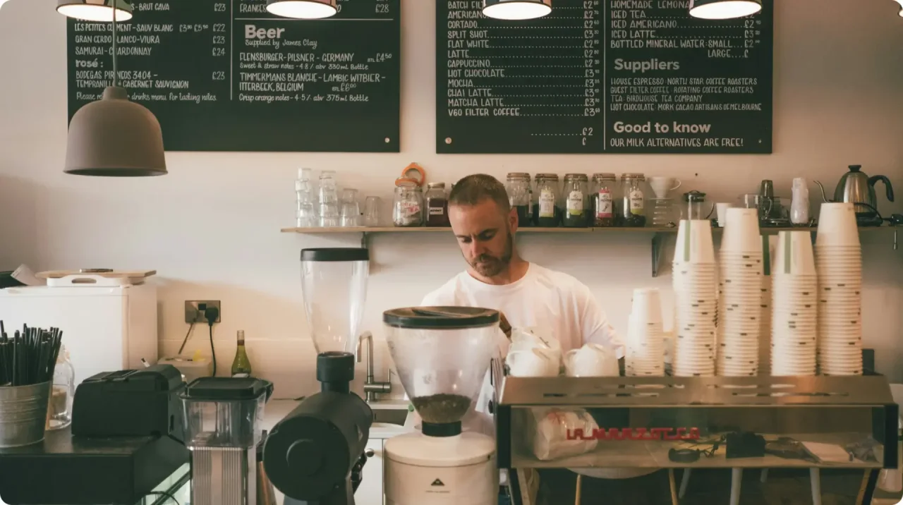 Barista Preparing Coffee Behind Counter In Cafe