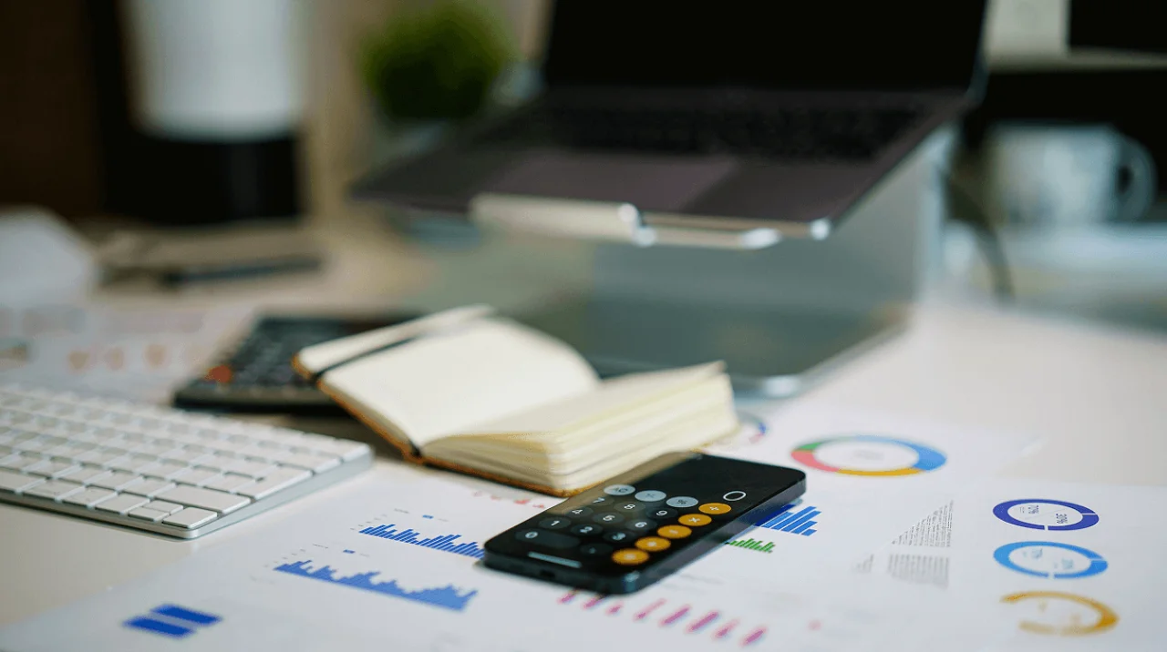 Solo entrepreneur reviewing compliance checklist and business documents at a kitchen table with coffee and laptop
