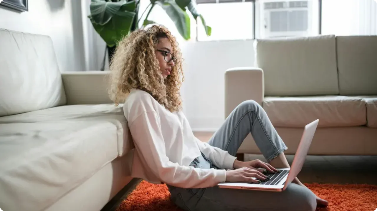 Woman Working On Laptop Sitting On Floor At Home