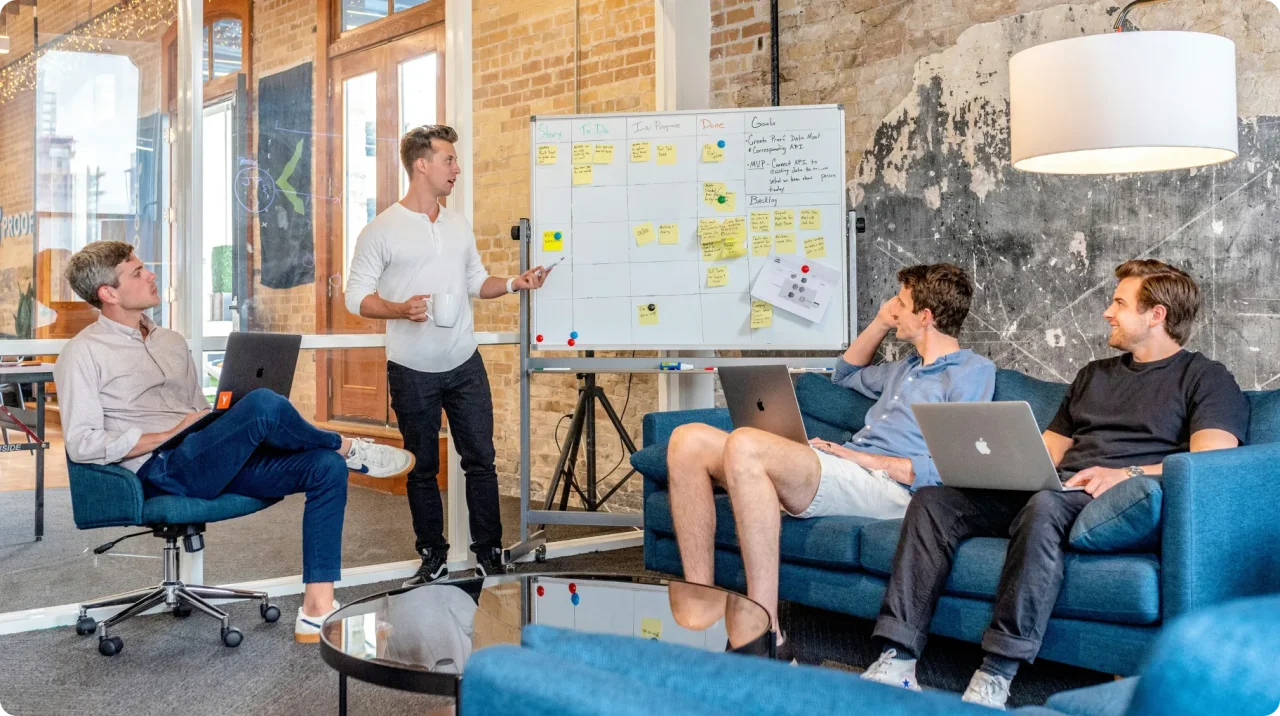 Team Brainstorming Session With Whiteboard And Laptops