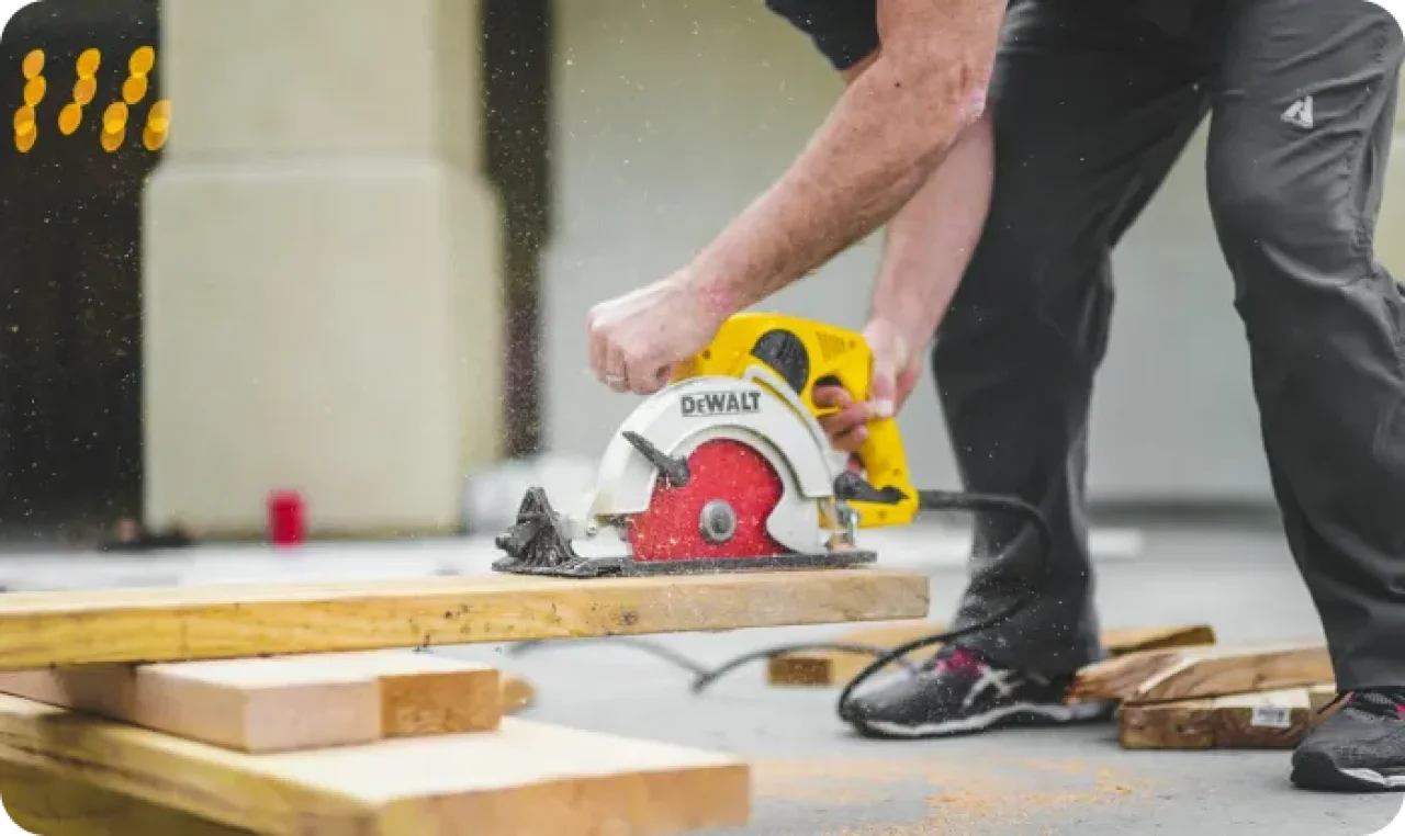 Man In Black Sweatpants Using Dewalt Circular Saw And Cutting A Wood Plank