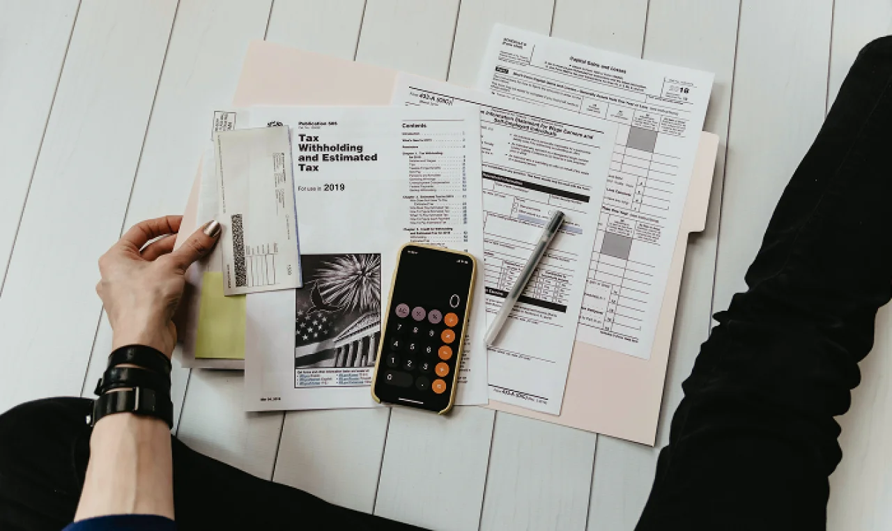 Solo entrepreneur sitting on a couch with a laptop and paperwork, working on building a legally compliant business while managing finances on a tight budget.