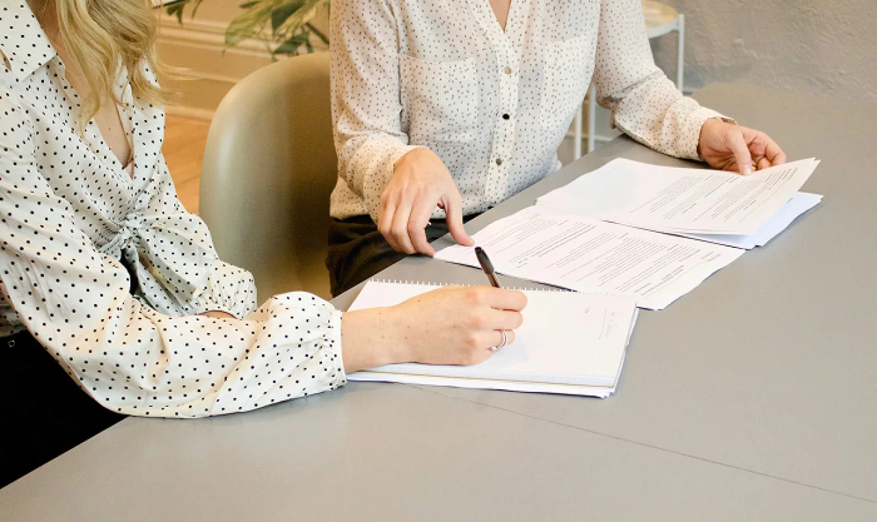 Solo entrepreneur reviewing a contract template at a desk with a laptop, coffee mug, and open notebook