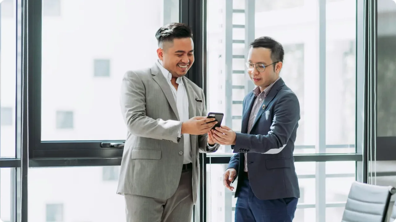 Two business professionals reviewing information on a smartphone in a modern office setting