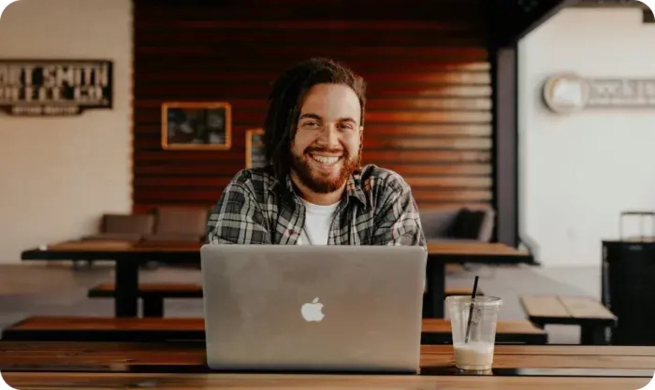 Man smilling from behind of a macbook