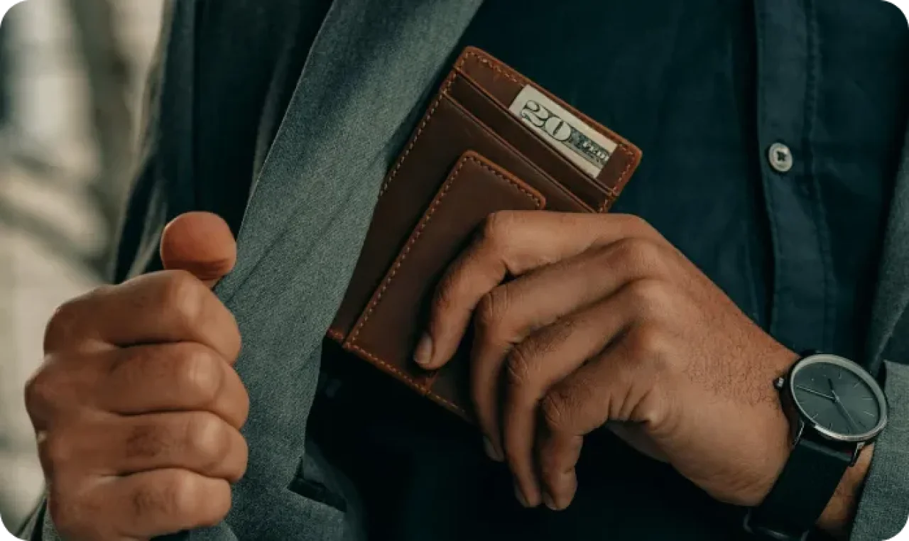 Person holding a wallet in a suit jacket pocket.