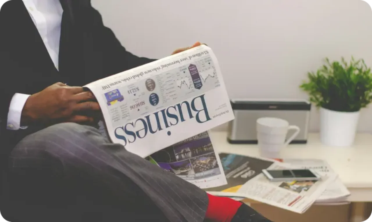 Person sitting near table holding newspaper