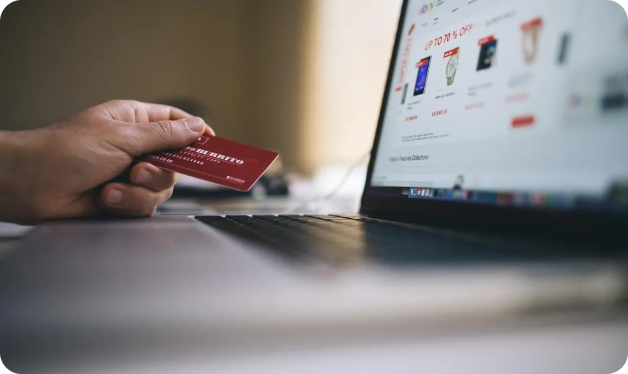 Person holding credit card while shopping online on a laptop.